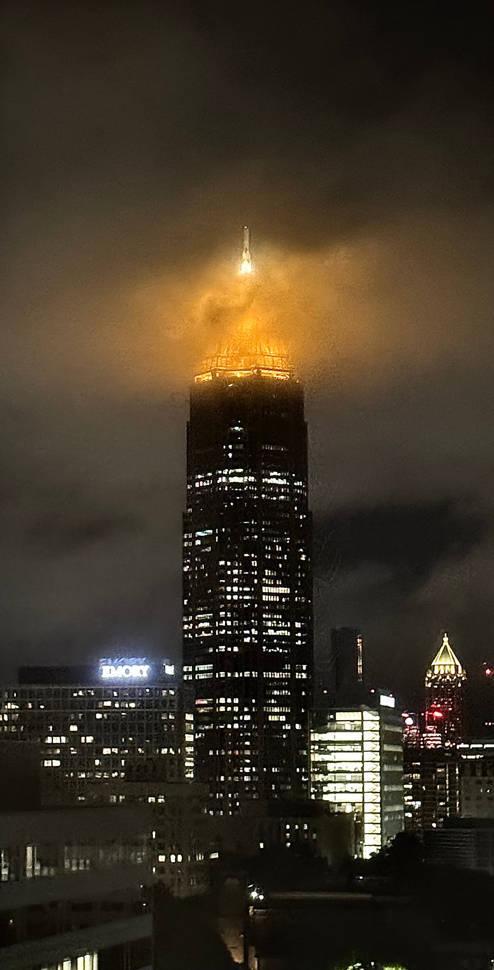 A tower glowing through low clouds at night in Atlanta