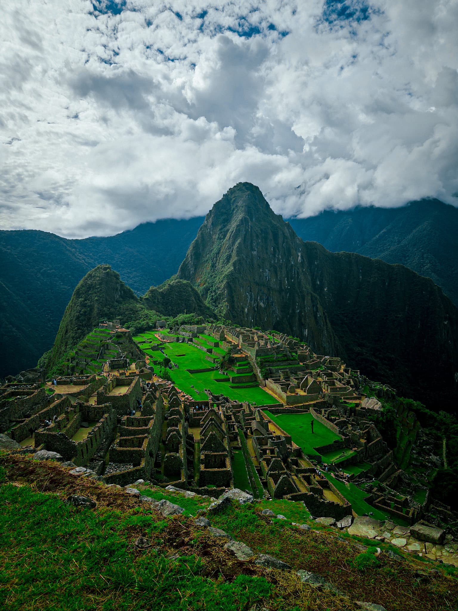The green terraces of Machu Picchu beneath a cloudy sky